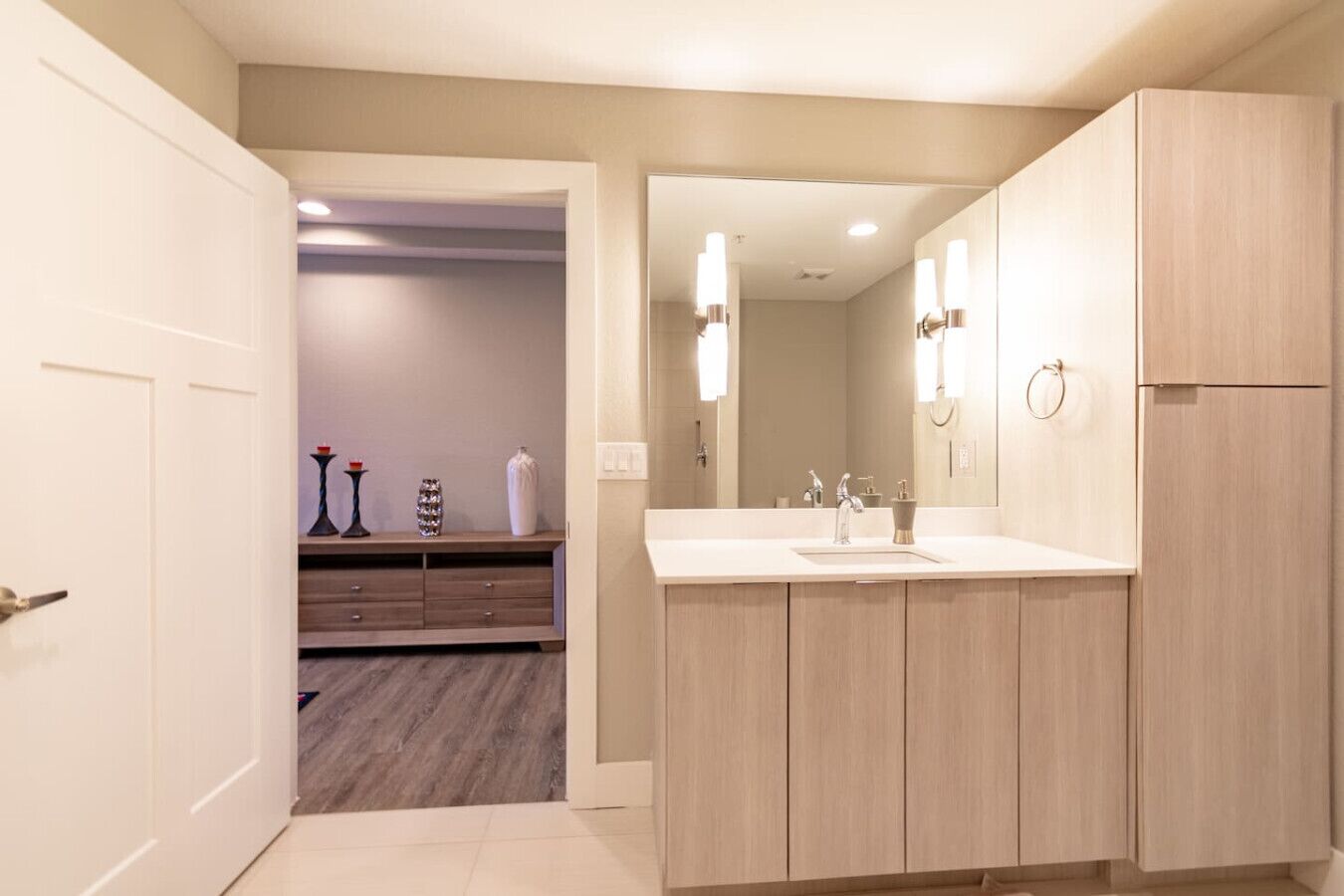 Un baño moderno con un espejo grande, armarios de madera y un tocador con lavamanos.