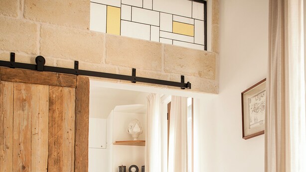 A hallway with a wooden door, a staircase, and a shelf with decorative items. - Casa Katha by Monholiday (Monopoli)