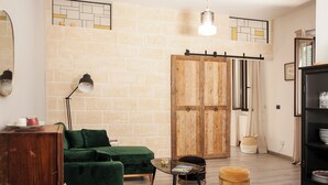 A living room with a green sofa, a wooden cabinet, a black floor lamp, and a wooden door. - Casa Katha by Monholiday (Monopoli)