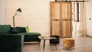 A modern living room with a green sofa, a small round table with glasses, a green bottle, and a wooden wardrobe. - Casa Katha by Monholiday (Monopoli)