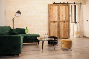 A modern living room with a green sofa, a small round table with glasses, a green bottle, and a wooden wardrobe. - Casa Katha by Monholiday (Monopoli)