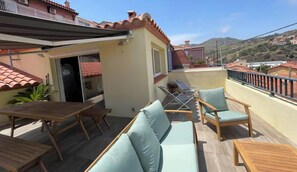 A balcony with wooden furniture, including a table and chairs, and a small enclosed area with a door. - Pretty "Terrace and Sea" house ideally located (Cerbère)