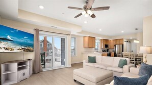 A modern living room with a sofa, a television, and a wooden coffee table. - Oceanside Condo Steps from the Beach and Boardwalk (Ocean City)