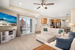 A modern living room with a sofa, a television, and a wooden coffee table. - Oceanside Condo Steps from the Beach and Boardwalk (Ocean City)