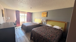A hotel room with two beds, a desk, and a window with curtains. - Wichita's Sunrise inn & Suites (Wichita)