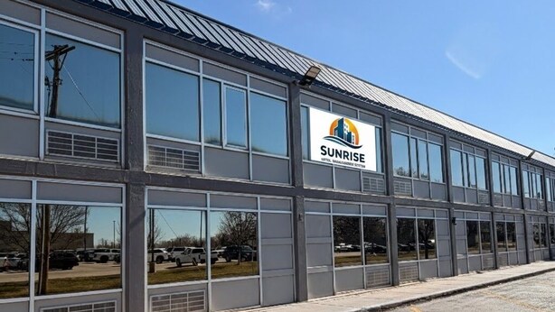 A modern building with large windows and a parking lot. - Wichita's Sunrise inn & Suites (Wichita)
