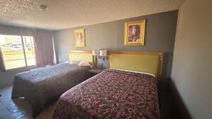 A hotel room with two beds, a window with curtains, a ceiling fan, and two framed pictures on the wall. - Wichita's Sunrise inn & Suites (Wichita)