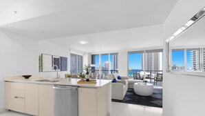 Eine moderne Wohnung mit Küche, Essbereich und Wohnzimmer, ausgestattet mit großen Fenstern und Blick auf hohe Gebäude.