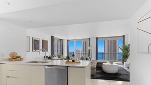 Eine moderne Küche mit Geschirrspüler, ein Essbereich mit Tisch und Stühlen sowie ein Wohnzimmer mit Sofa und Couchtisch.