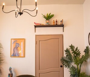 Een deur met een eenvoudig ontwerp, een klein schap erboven met decoratieve objecten, en een lijst met een foto aan de muur.
