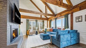 A spacious living room with a large sectional sofa, a fireplace, and a television mounted on the wall. - Mtn Views | Stargazing Dome | Hot Tub | Sleeps 20 (Fairview)
