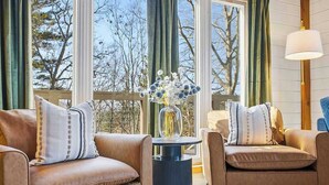 A cozy living room with leather sofas, a round side table, and a vase of flowers. - Mtn Views | Stargazing Dome | Hot Tub | Sleeps 20 (Fairview)