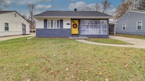 A single-story house with a yellow front door, a small porch, and a garage. - Cozy 2BR/1BA Ranch - Near Downtown Royal Oak (Oak Park)