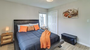 A bedroom with a bed, bedside table, lamp, artwork, and a bench. - Cozy 2BR/1BA Ranch - Near Downtown Royal Oak (Oak Park)