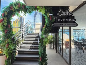 Eine Treppe führt zu einer Dachterrasse, auf der ein Schild 'Osaka Toscana Rooftop' steht.