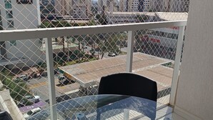 Ein Balkon mit Glastisch und Stühlen, mit Blick auf einen Parkplatz und Gebäude.