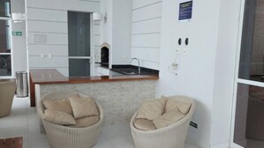Eine moderne Küche mit Einbauofen, Spüle und Holz Arbeitsplatte. Zwei Korbstühle mit Kissen und ein Holztisch sind ebenfalls vorhanden.