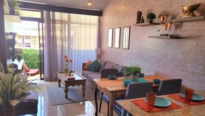 A modern living room with a sofa, coffee table, and dining table. There are potted plants and decorative items on the walls. - Near Airport, Lush Gardens, Pool, King Bed, Security SANTA ANA NEAR DOWNTOWN (Santa Ana)