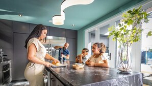 Una cocina moderna con armarios oscuros, encimera de mármol y un amplio ventanal.