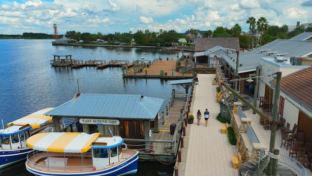 A waterfront dock with boats, a pier, and buildings with outdoor seating. - Pet friendly Charming Bonnybrook Villa! (The Villages)