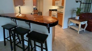 A kitchen with a bar area, wooden stools, and a white countertop. - Pet friendly Charming Bonnybrook Villa! (The Villages)