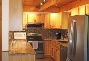 A kitchen with wooden cabinets, a stainless steel refrigerator, a microwave, an oven, and a coffee maker. - Peaceful Cabin Retreat Near Mayfield Lake- Boating, Fishing, Hunting, Hiking (Silver Creek)