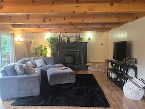 A cozy living room with a fireplace, a sectional sofa, a black rug, and a television. - Peaceful Cabin Retreat Near Mayfield Lake- Boating, Fishing, Hunting, Hiking (Silver Creek)