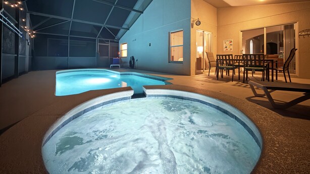 Ein Innenpool mit Whirlpool, einer überdachten Terrasse und einem Esstisch mit Stühlen.