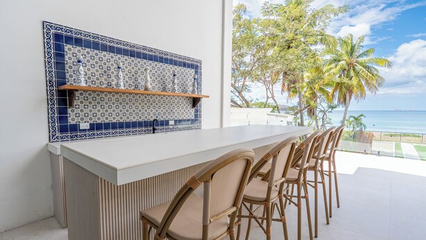 A bar area with a tiled backsplash, wicker chairs, and a view of the ocean. - Luxury Beachfront Mansion (Provincia de Guanacaste)