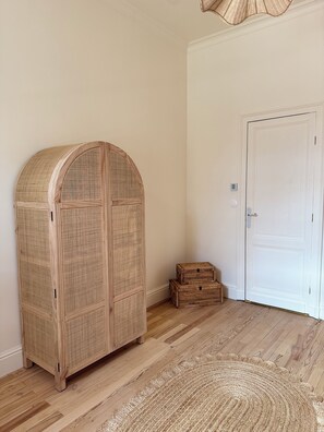 A room with a wooden wardrobe, a white door, and a woven rug on a wooden floor. - Stunning Villa in the Arcachon Basin with a Pool (Audenge)