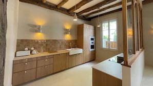 A kitchen with wooden cabinets, a countertop, a sink, and a window. - Stunning Villa in the Arcachon Basin with a Pool (Audenge)