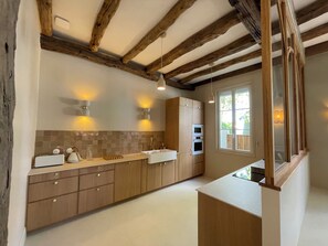 A kitchen with wooden cabinets, a countertop, a sink, and a window. - Stunning Villa in the Arcachon Basin with a Pool (Audenge)