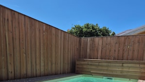 A wooden deck surrounding a rectangular swimming pool with a wooden fence in the background. - Stunning Villa in the Arcachon Basin with a Pool (Audenge)