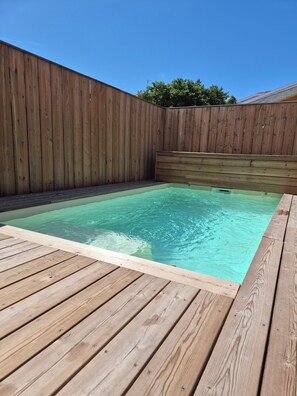 A wooden deck surrounding a rectangular swimming pool with a wooden fence in the background. - Stunning Villa in the Arcachon Basin with a Pool (Audenge)