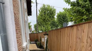 A narrow pathway with gravel, bordered by a wooden fence and a brick wall. - Stunning Villa in the Arcachon Basin with a Pool (Audenge)