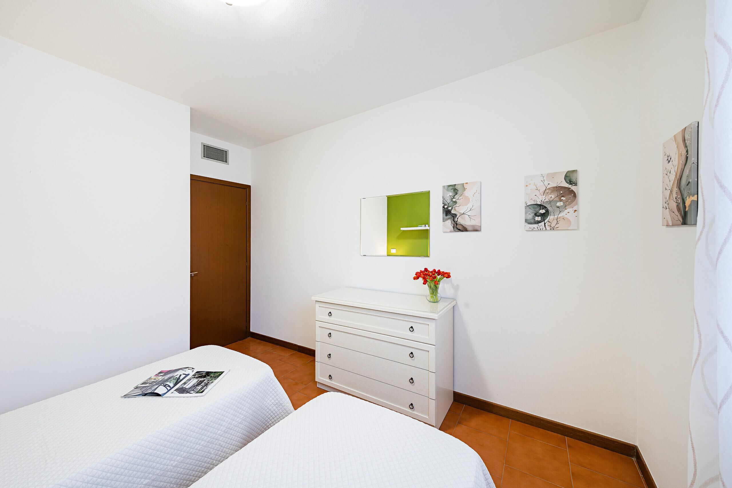 Habitación de hotel con dos camas, un tocador y obras de arte en las paredes.