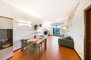 Una cucina moderna con un tavolo da pranzo per quattro persone, un divano e una scala che conduce a un balcone.