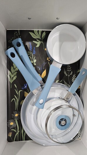 A box containing a white plate, a blue-handled spoon, and a blue-handled fork. - Newly Furnished Private Suite | Separate Entry, Kitchen, Laundry & Workspace (Regina)