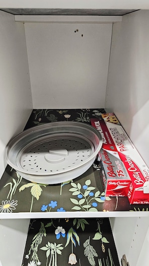 A kitchen with a stainless steel colander on the counter, a box of Betty Crocker paper towels, and a floral-patterned tablecloth. - Newly Furnished Private Suite | Separate Entry, Kitchen, Laundry & Workspace (Regina)