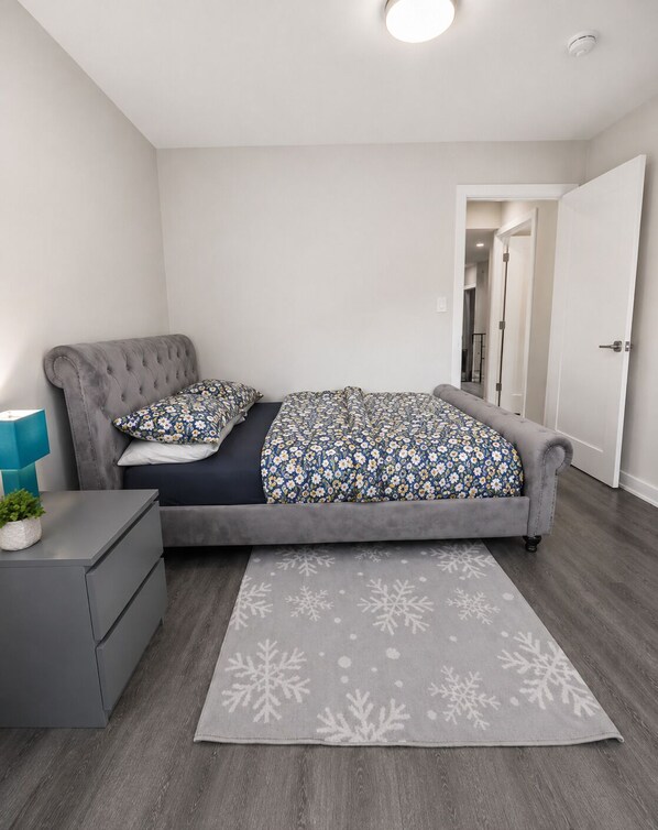 A bedroom with a bed, bedside tables, a lamp, and a door. - Newly Furnished Private Suite | Separate Entry, Kitchen, Laundry & Workspace (Regina)