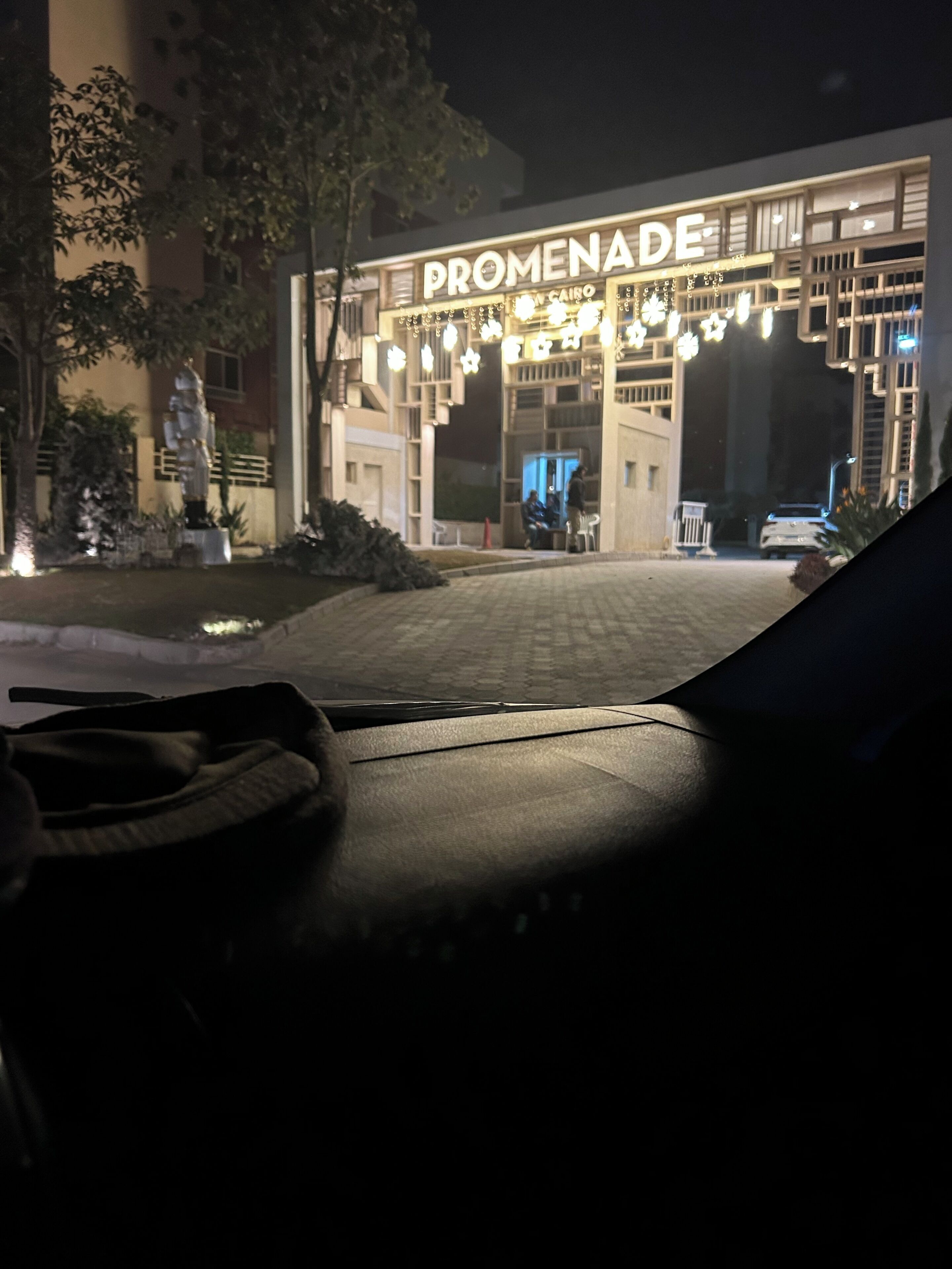 Ein Nachtbild von einem Gebäudeeingang, dessen Schild 'PROMENADE' beleuchtet ist.