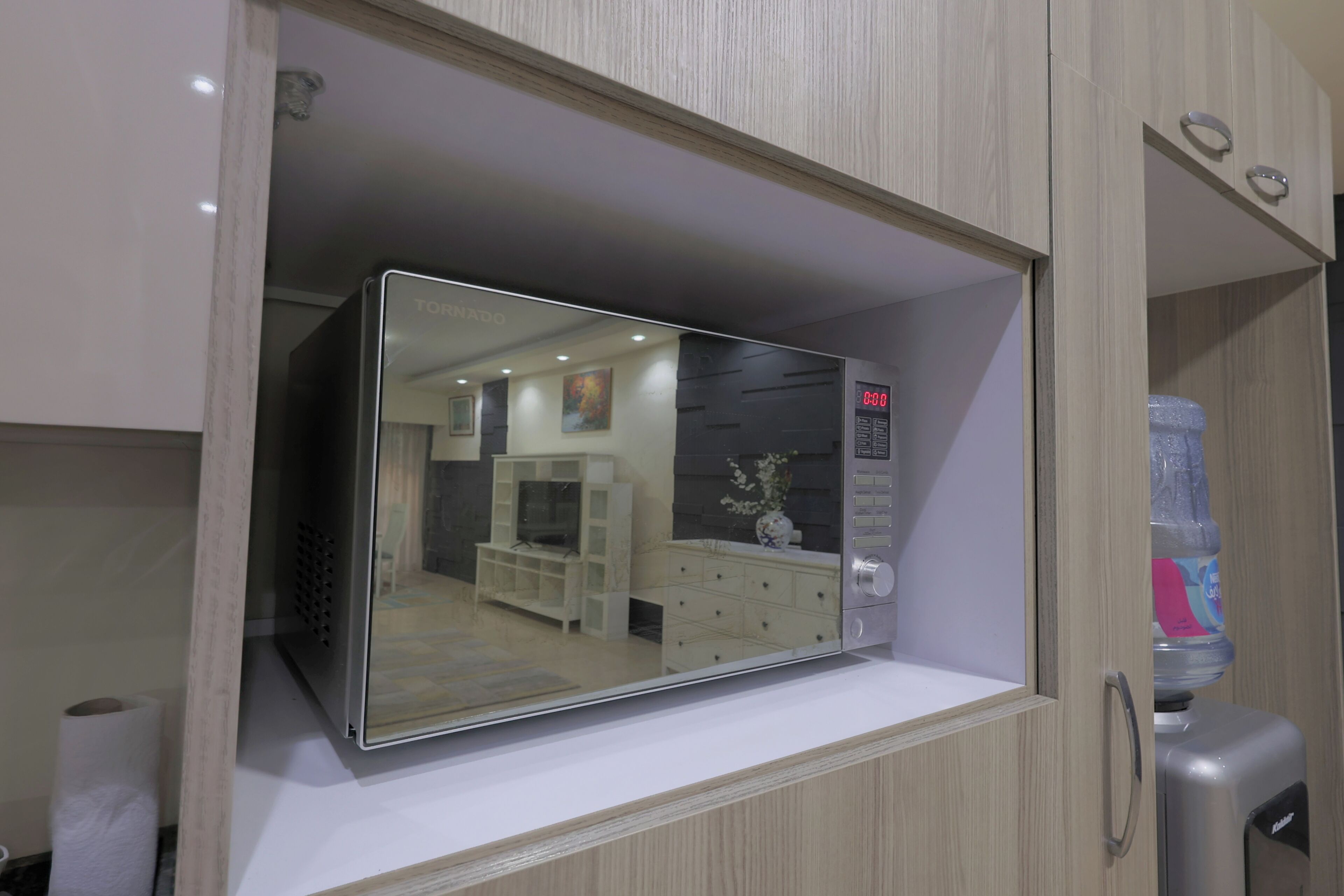 A room with a mirrored wardrobe, a water dispenser, and a white dresser.