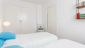 Ein Schlafzimmer mit Bett, Stuhl, Bücherregal und Kleiderschrank.