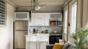 Une cuisine moderne avec des meubles blancs, un îlot central doté de tabourets de bar, un réfrigérateur en acier inoxydable et une cuisinière à gaz.