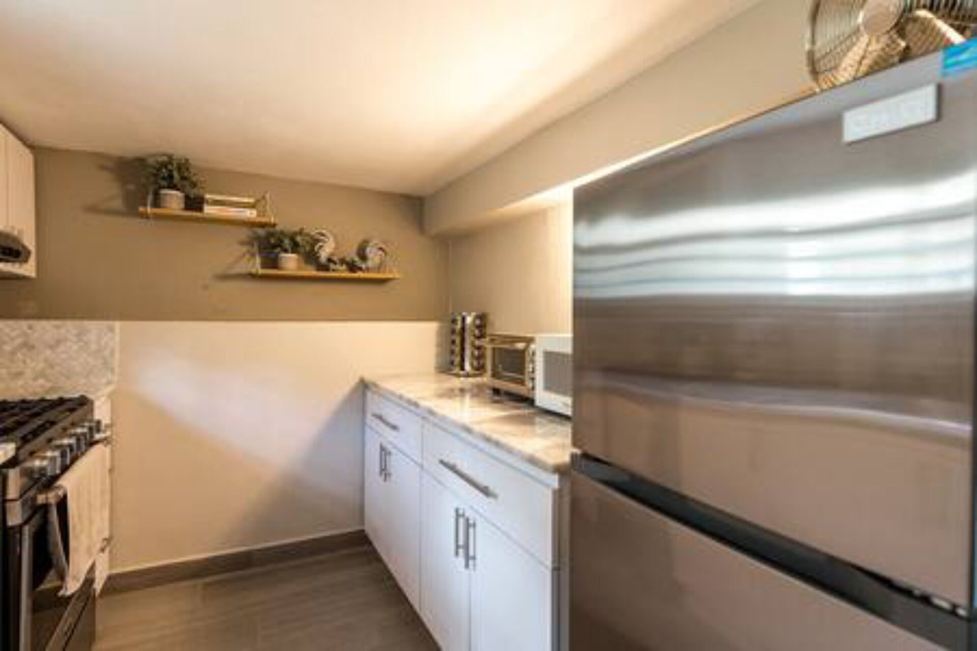 A kitchen with white cabinets, a stainless steel refrigerator, a microwave, and a stove.