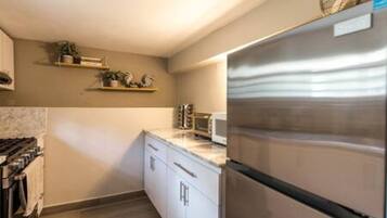 A kitchen with white cabinets, a stainless steel refrigerator, a microwave, and a stove.