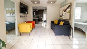 A spacious living area with a sofa, chairs, and a TV. - Oasis at Hacienda el Lago (Cayey)