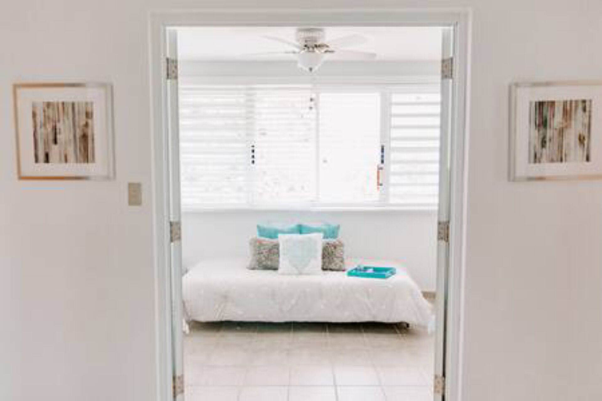 A bedroom with a bed, a ceiling fan, and a window with blinds.