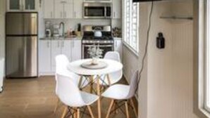 A modern kitchen with white cabinets, stainless steel appliances, and a dining area with a round table and chairs. - Reposo at Hacienda el Lago (Cayey)