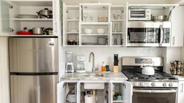 A modern kitchen with stainless steel appliances, white cabinetry, and a built-in oven. - Reposo at Hacienda el Lago (Cayey)